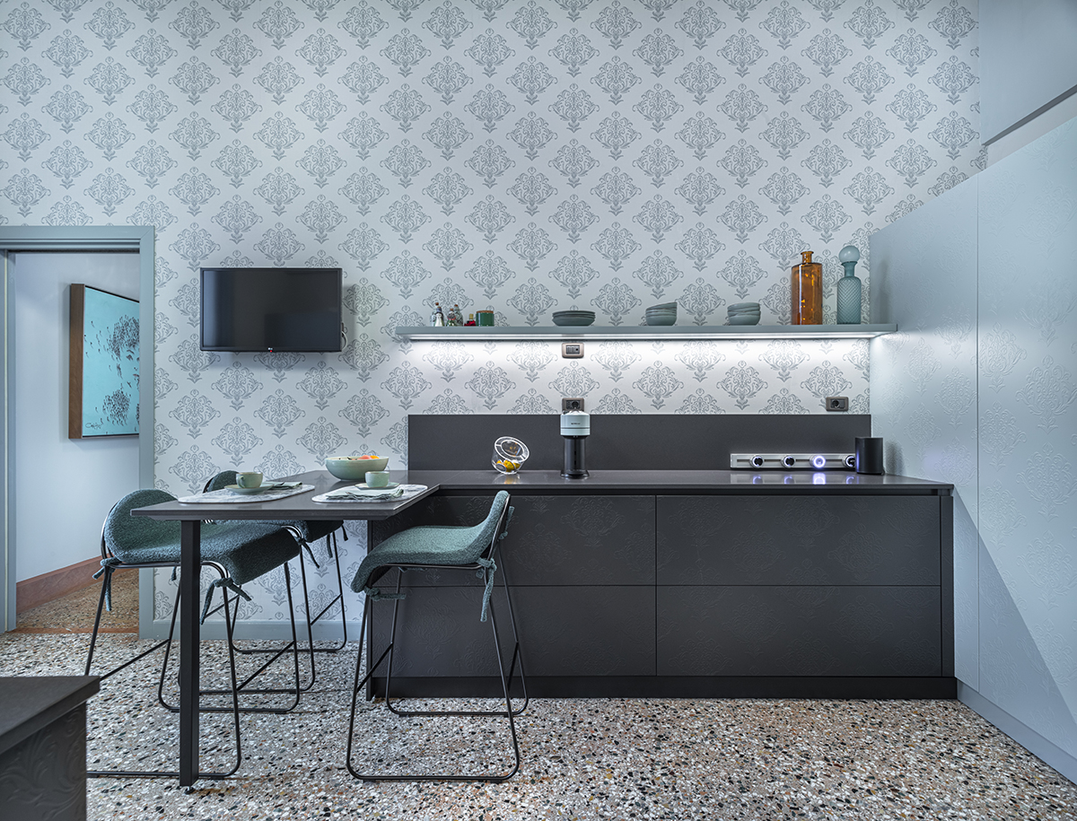 Cucina con mobili scuri e carta da parati